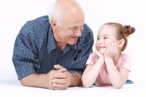 41041584 - portrait of a grandfather wearing blue checkered shirt and his small pretty granddaughter lying near looking at each other and smiling, isolated on a white background